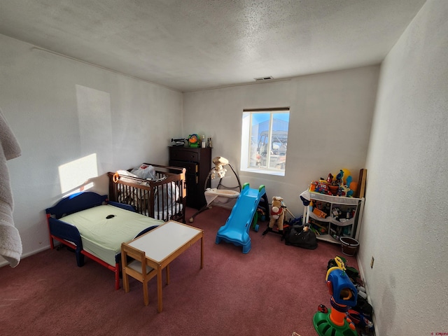 bedroom with carpet, a nursery area, and a textured ceiling