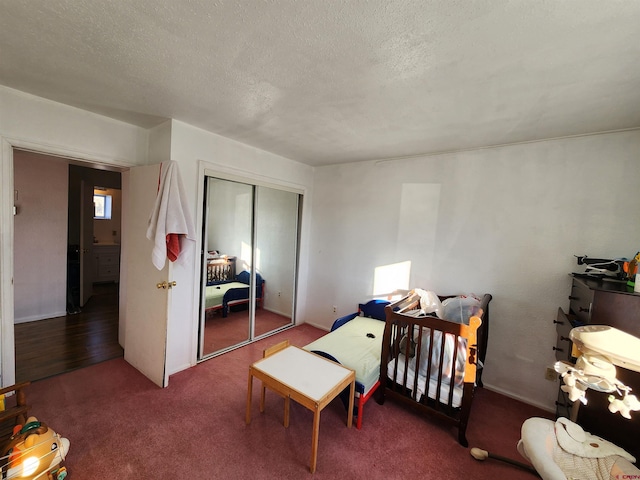 bedroom featuring carpet flooring, a nursery area, a textured ceiling, and a closet