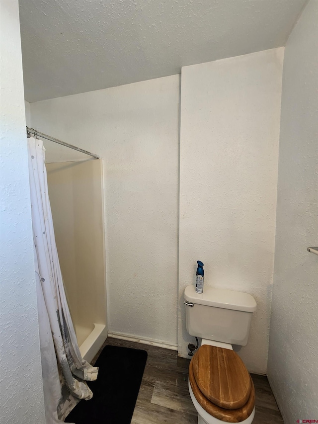 bathroom featuring wood-type flooring, toilet, and curtained shower