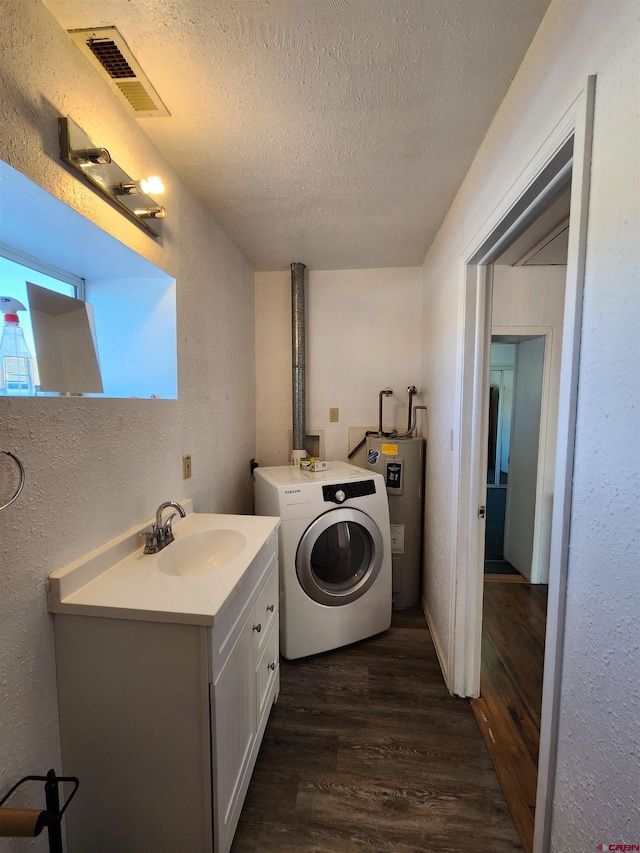 laundry area featuring washer / clothes dryer, water heater, dark wood-type flooring, and a textured ceiling