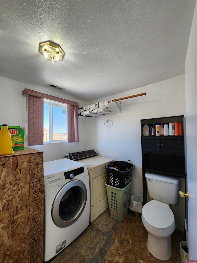 laundry room featuring a textured ceiling and washing machine and dryer