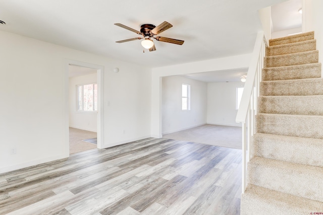 interior space with a ceiling fan, baseboards, stairway, and wood finished floors