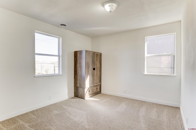 unfurnished bedroom with carpet, visible vents, and baseboards