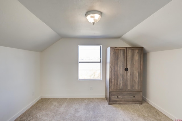 additional living space with lofted ceiling, light colored carpet, and baseboards