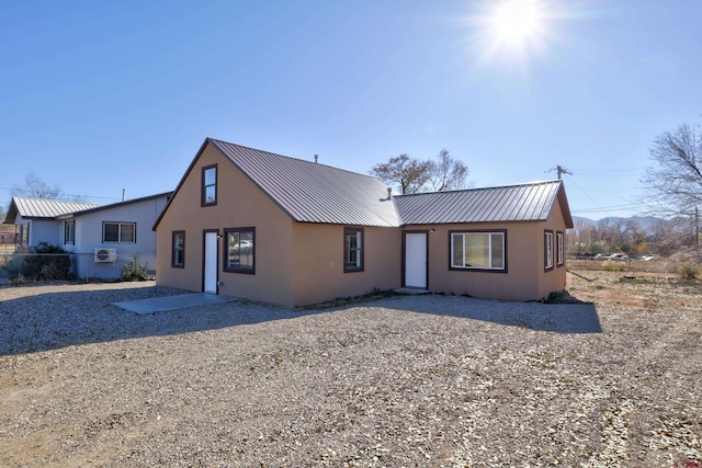 view of front of property with fence, metal roof, and stucco siding