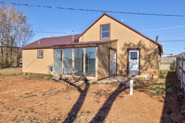 back of property with metal roof, a patio, fence, a sunroom, and stucco siding