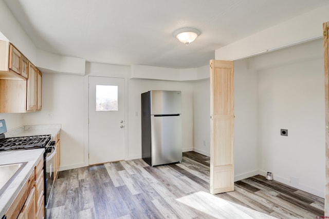 kitchen featuring light wood-type flooring, baseboards, appliances with stainless steel finishes, and light countertops