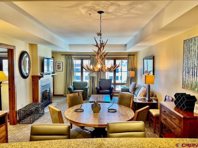 dining area featuring a raised ceiling, light carpet, and a chandelier