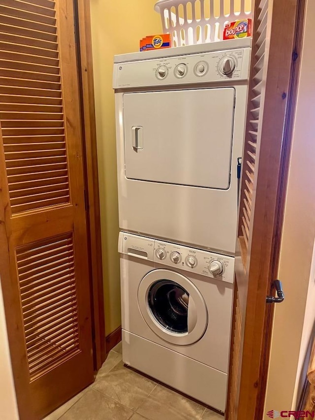 laundry area with light tile patterned floors and stacked washer and clothes dryer