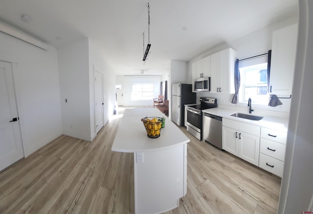 kitchen with white cabinets, appliances with stainless steel finishes, a kitchen island, and a healthy amount of sunlight