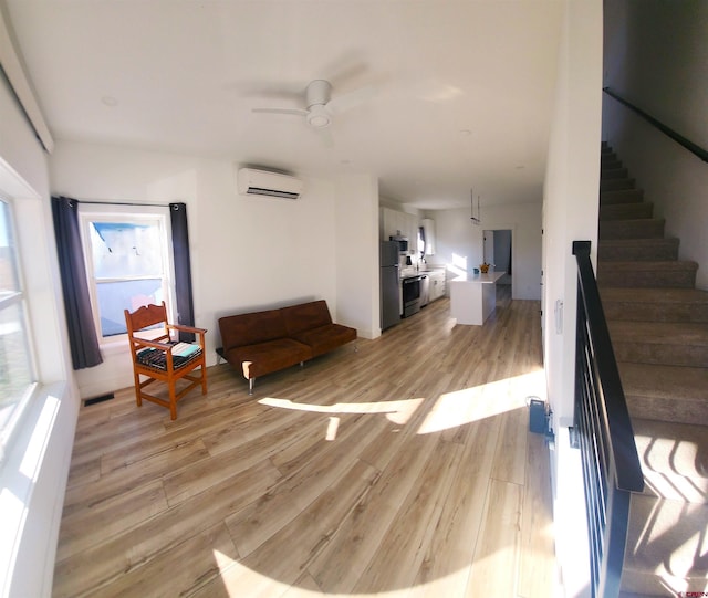 interior space with a wealth of natural light, a wall unit AC, and light hardwood / wood-style flooring