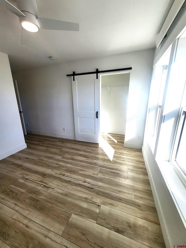 interior space with ceiling fan, a barn door, a closet, and light hardwood / wood-style flooring