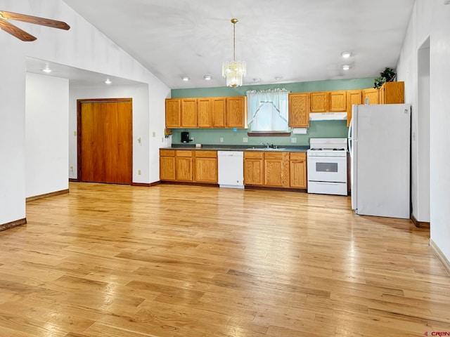 kitchen with white appliances, sink, hanging light fixtures, vaulted ceiling, and light hardwood / wood-style floors