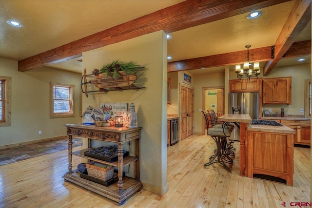 kitchen featuring beamed ceiling, light hardwood / wood-style floors, and an inviting chandelier