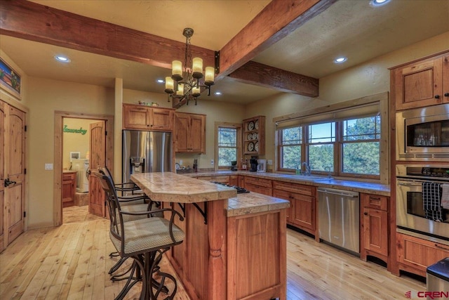 kitchen with a chandelier, light hardwood / wood-style floors, decorative light fixtures, and appliances with stainless steel finishes