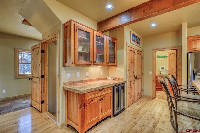 kitchen with stainless steel fridge, beamed ceiling, beverage cooler, and light hardwood / wood-style floors