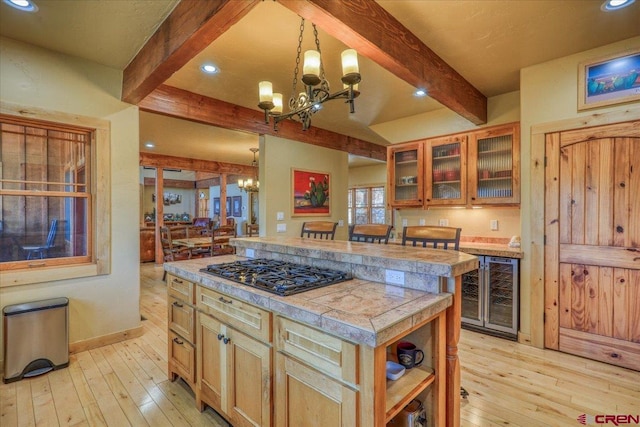 kitchen featuring wine cooler, black gas cooktop, a chandelier, light hardwood / wood-style floors, and a kitchen island