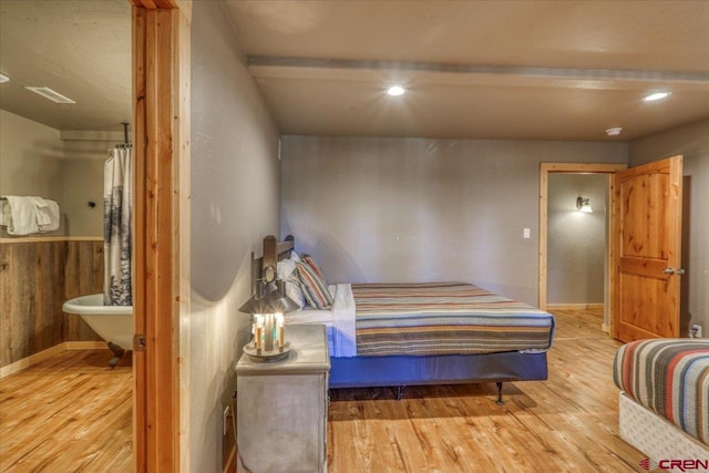 bedroom featuring light hardwood / wood-style flooring and wooden walls