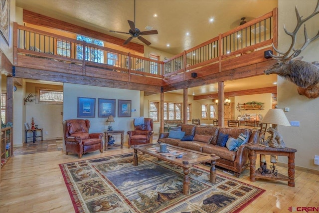 living room with ceiling fan with notable chandelier, a high ceiling, and light hardwood / wood-style flooring