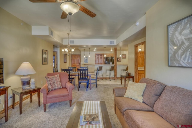 living room with ceiling fan with notable chandelier and light colored carpet