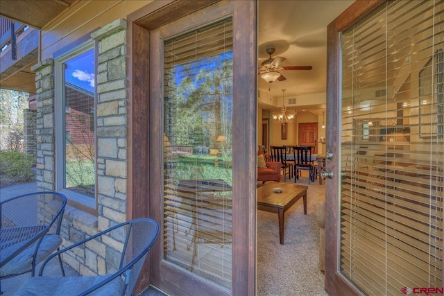 entryway with ceiling fan with notable chandelier and carpet flooring