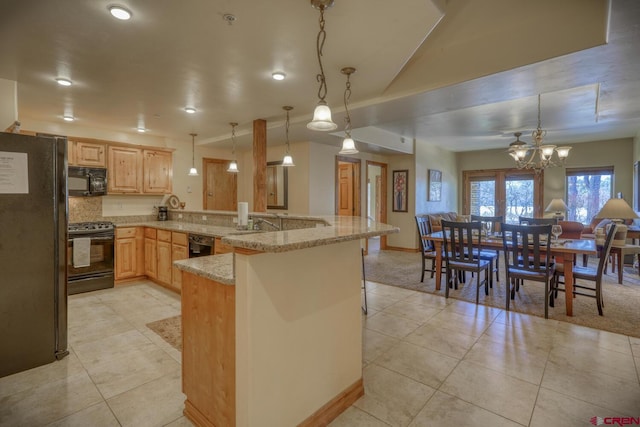 kitchen with light stone counters, pendant lighting, black appliances, and light brown cabinets