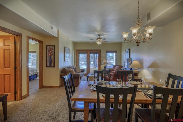 carpeted dining area featuring ceiling fan with notable chandelier and french doors