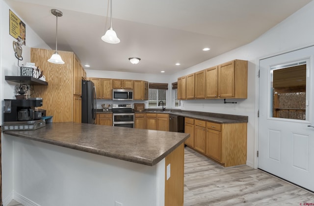 kitchen with kitchen peninsula, appliances with stainless steel finishes, sink, light hardwood / wood-style floors, and hanging light fixtures