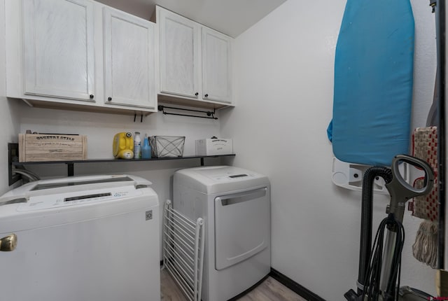 laundry room featuring washer and clothes dryer, cabinets, and light wood-type flooring