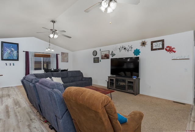 living room featuring ceiling fan with notable chandelier, light hardwood / wood-style floors, and vaulted ceiling