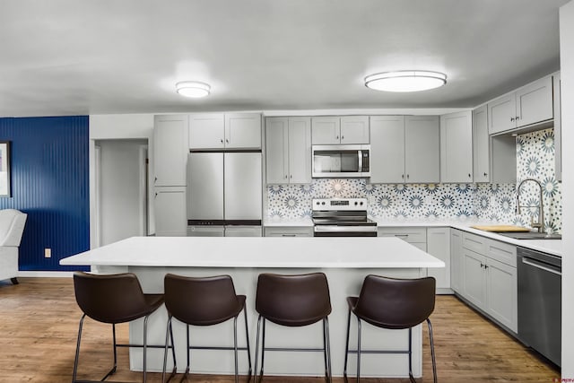 kitchen with stainless steel appliances, a center island, sink, and light hardwood / wood-style flooring