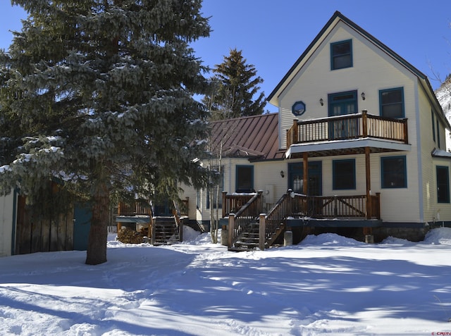 snow covered property featuring a balcony and covered porch