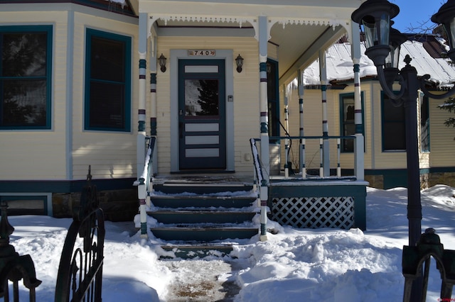 snow covered property entrance featuring covered porch