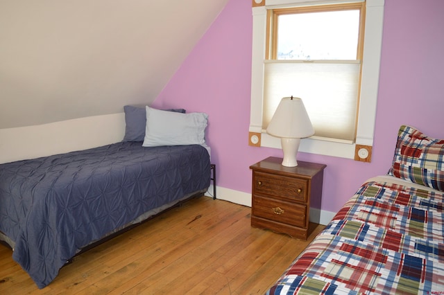 bedroom with lofted ceiling and light wood-type flooring