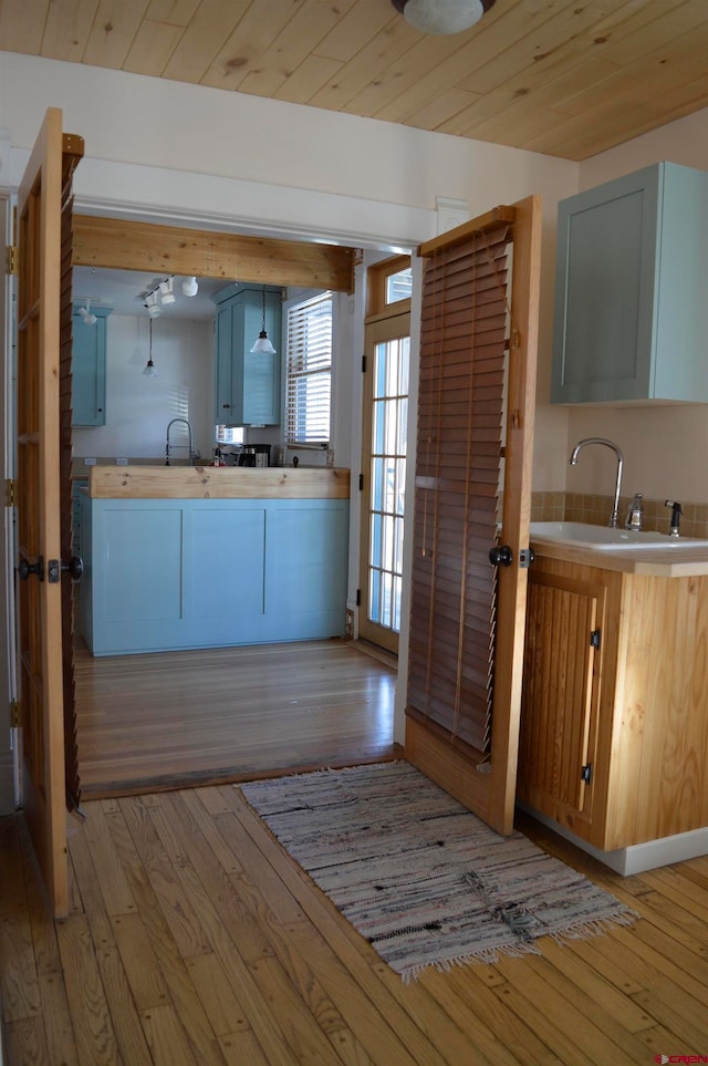 kitchen featuring light hardwood / wood-style floors, wooden ceiling, and sink