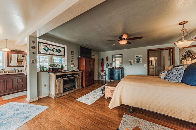 bedroom featuring a textured ceiling, ceiling fan, ensuite bathroom, and light hardwood / wood-style flooring