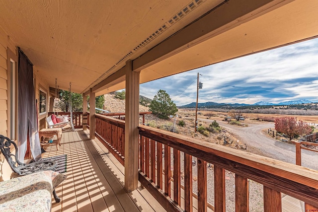 wooden deck with a mountain view and a porch