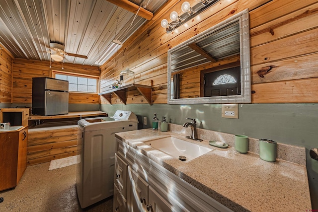 interior space featuring independent washer and dryer, ceiling fan, wooden walls, and sink