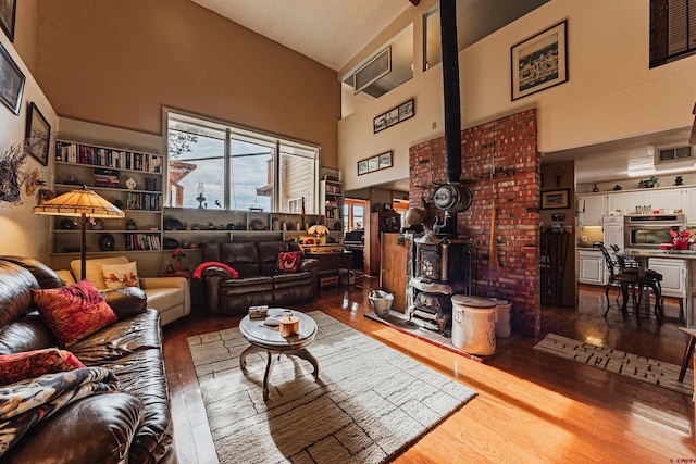 living room with hardwood / wood-style floors, a wood stove, and high vaulted ceiling