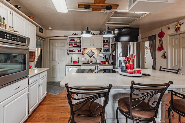 kitchen featuring white cabinets, appliances with stainless steel finishes, decorative light fixtures, and dark hardwood / wood-style floors