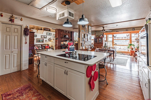 kitchen with white cabinetry, a center island, hardwood / wood-style floors, decorative light fixtures, and black electric stovetop