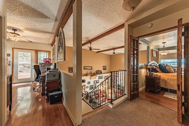 hallway featuring beamed ceiling, wood-type flooring, and a textured ceiling