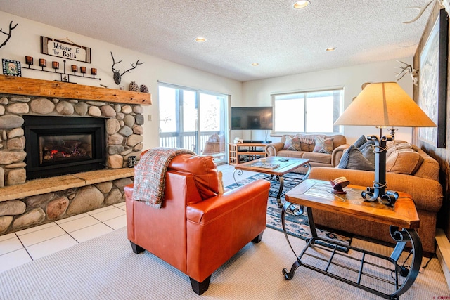 tiled living room featuring a textured ceiling and a stone fireplace