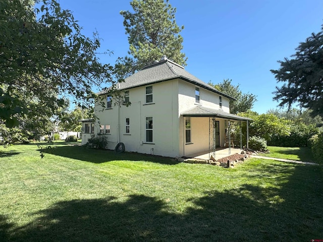 rear view of house featuring a patio area and a yard