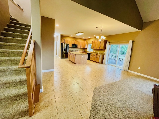 kitchen with hanging light fixtures, a kitchen island, a notable chandelier, light tile patterned flooring, and black appliances