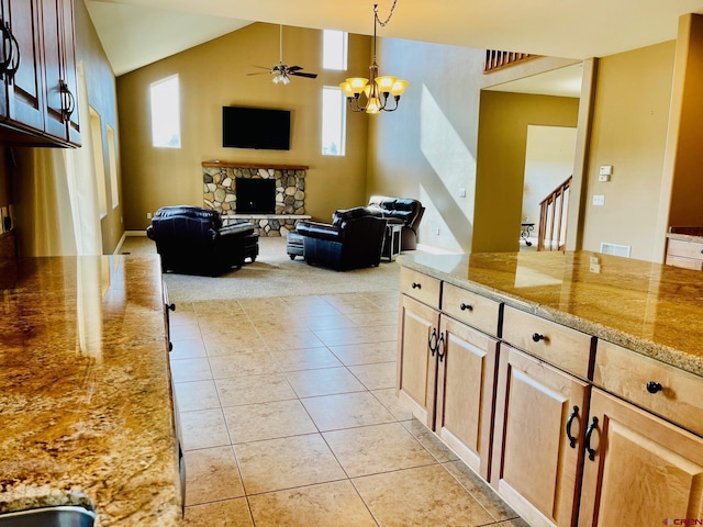 interior space featuring ceiling fan with notable chandelier, light tile patterned floors, a fireplace, and vaulted ceiling