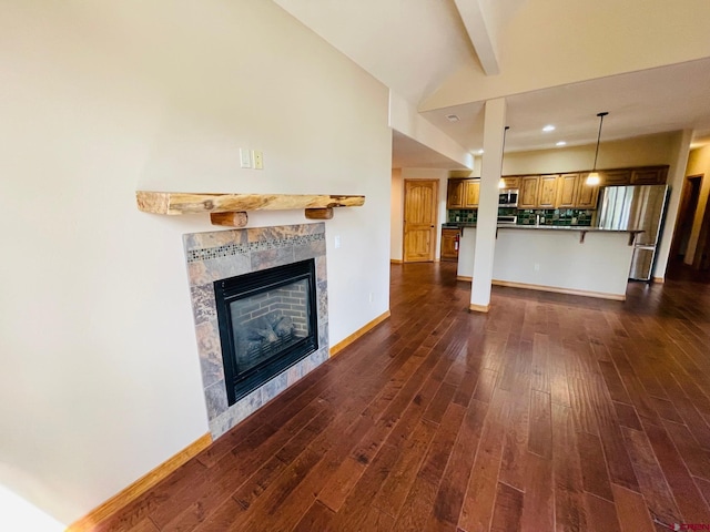 unfurnished living room featuring a tile fireplace, lofted ceiling, and dark hardwood / wood-style floors