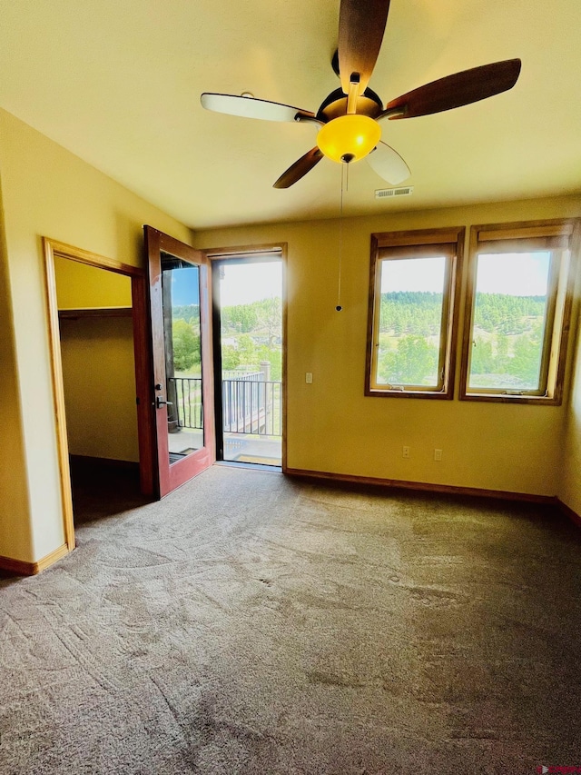 carpeted empty room with a wealth of natural light and ceiling fan