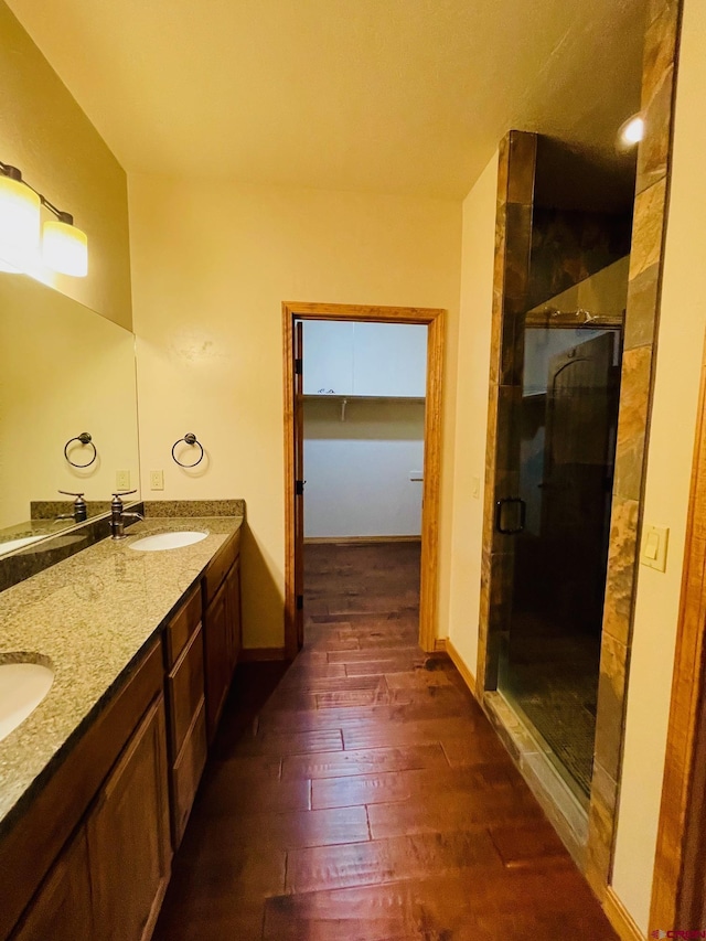 bathroom with hardwood / wood-style floors, vanity, and a shower with shower door