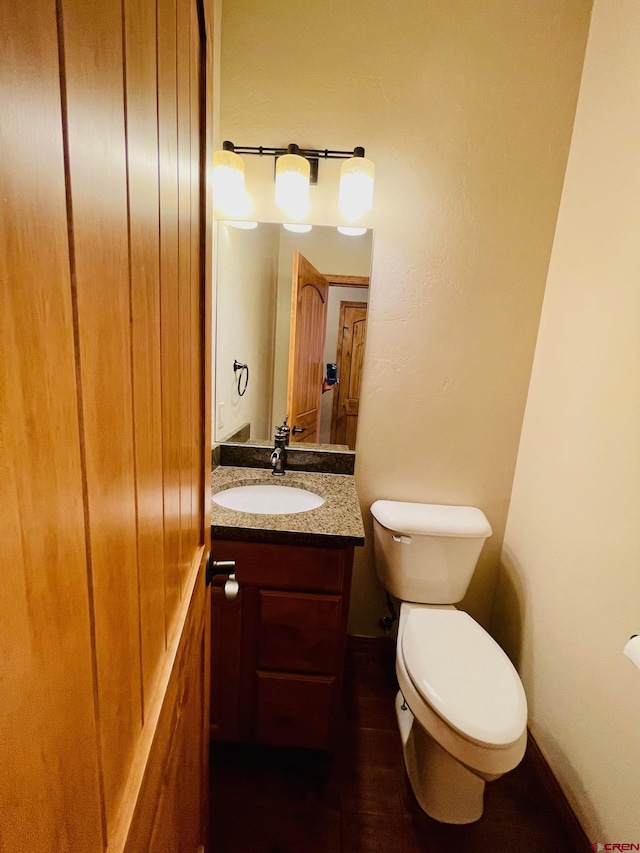 bathroom with hardwood / wood-style flooring, vanity, and toilet